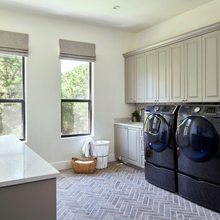 Photo of a traditional galley utility room in Other with a submerged sink, raised-panel cabinets, grey cabinets, white walls, brick flooring, a side by side washer and dryer, brown floors and beige worktops.