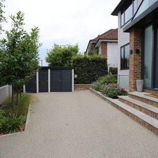 This is an example of a medium sized modern front formal garden in London with gravel.