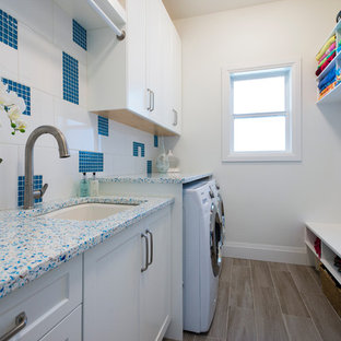 Inspiration for a medium sized classic galley utility room in Vancouver with a submerged sink, shaker cabinets, white cabinets, recycled glass countertops, grey walls, porcelain flooring and a side by side washer and dryer.