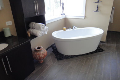 This is an example of a mid-sized contemporary master bathroom in Seattle with black cabinets, a freestanding tub, beige walls, dark hardwood floors, an undermount sink, granite benchtops and brown floor.