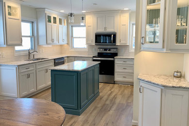 Example of a mid-sized beach style u-shaped vinyl floor eat-in kitchen design in Other with flat-panel cabinets, blue cabinets, quartz countertops, white backsplash, porcelain backsplash, stainless steel appliances, an island and multicolored countertops