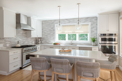 Example of a huge transitional l-shaped light wood floor eat-in kitchen design in Providence with an undermount sink, shaker cabinets, white cabinets, quartz countertops, gray backsplash, ceramic backsplash, stainless steel appliances, an island and white countertops