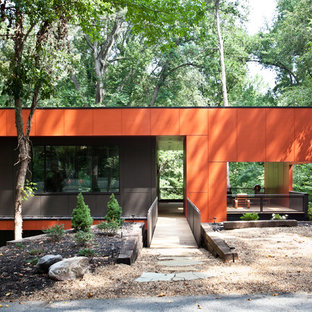 На фото: одноэтажные фасады домов среднего размера оранжевого цвета в стиле модернизм
