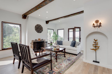 Inspiration for a mid-sized mediterranean formal and open concept light wood floor and brown floor living room remodel in Los Angeles with white walls, a standard fireplace, a stone fireplace and no tv