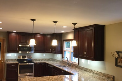 Kitchen - kitchen idea in New York with an undermount sink, raised-panel cabinets, dark wood cabinets, granite countertops, stone slab backsplash and stainless steel appliances