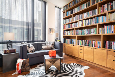 Photo of a large contemporary open concept family room in New York with a library, white walls and brown floor.