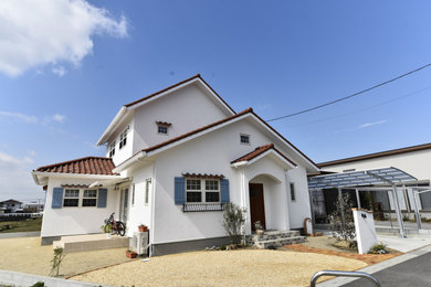 Imagen de fachada de casa blanca y marrón de dos plantas con tejado de teja de barro