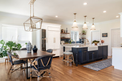 Mid-sized transitional medium tone wood floor and brown floor kitchen photo in St Louis with a farmhouse sink, shaker cabinets, blue cabinets, quartz countertops, blue backsplash, porcelain backsplash, paneled appliances, an island and white countertops