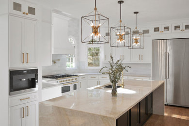 Large trendy l-shaped medium tone wood floor and brown floor eat-in kitchen photo in Atlanta with an undermount sink, shaker cabinets, white cabinets, quartzite countertops, white backsplash, ceramic backsplash, stainless steel appliances, an island and beige countertops