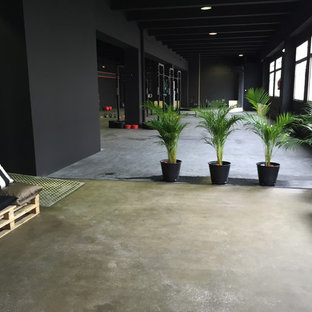 他の地域の巨大なインダストリアルスタイルのおしゃれな多目的ジム (黒い壁、コンクリートの床) の写真