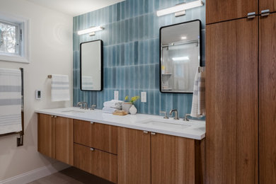 Bathroom - master blue tile and porcelain tile porcelain tile, gray floor and double-sink bathroom idea in Boston with flat-panel cabinets, medium tone wood cabinets, a two-piece toilet, beige walls, an undermount sink, solid surface countertops, white countertops and a floating vanity