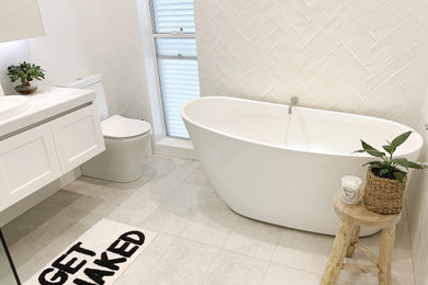 Design ideas for a mid-sized contemporary master bathroom in Sydney with white cabinets, a freestanding tub, a corner shower, white tile, subway tile, solid surface benchtops, a hinged shower door, white benchtops, a single vanity and a floating vanity.