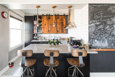 This is an example of a mid-sized industrial u-shaped separate kitchen in San Francisco with an undermount sink, flat-panel cabinets, black cabinets, quartz benchtops, white splashback, subway tile splashback, stainless steel appliances and a peninsula.