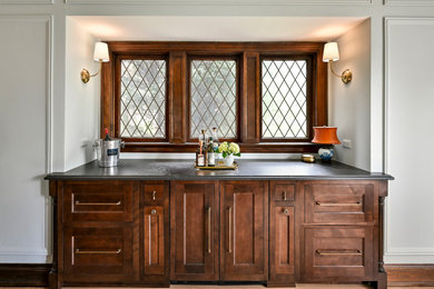 Inspiration for a timeless single-wall light wood floor and beige floor dry bar remodel in Milwaukee with shaker cabinets, dark wood cabinets and black countertops