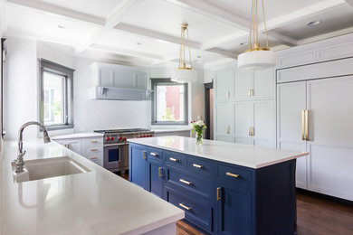 This is an example of a transitional u-shaped open plan kitchen in Boston with an integrated sink, shaker cabinets, blue cabinets, granite benchtops, white splashback, porcelain splashback, panelled appliances, dark hardwood floors, with island and brown floor.