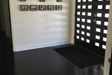 This is an example of a mid-sized contemporary foyer in Baltimore with white walls, dark hardwood floors, a double front door, a black front door and black floor.