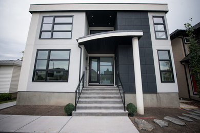 Huge modern gray three-story stucco exterior home idea in Calgary with a shingle roof