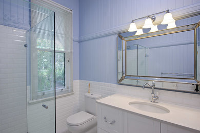 This is an example of a mid-sized traditional 3/4 bathroom in Brisbane with shaker cabinets, white cabinets, a corner shower, a one-piece toilet, purple walls, ceramic floors, an undermount sink, white floor, a hinged shower door, white tile and subway tile.