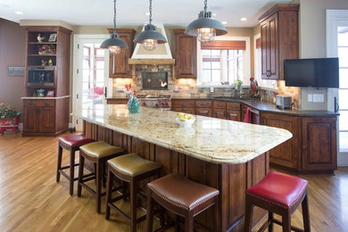 This is an example of a large country galley open plan kitchen in San Diego with a single-bowl sink, raised-panel cabinets, medium wood cabinets, beige splashback, stainless steel appliances, medium hardwood floors, with island and brown floor.