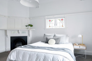 Ejemplo de habitación de invitados actual con paredes blancas, moqueta, chimenea de esquina y suelo gris