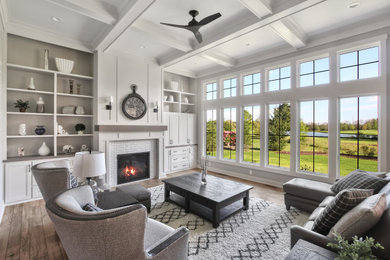 Design ideas for a large country open concept living room in Milwaukee with grey walls, medium hardwood floors, a standard fireplace, a tile fireplace surround, a concealed tv, brown floor, coffered and panelled walls.