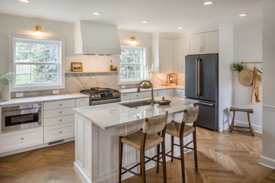 Mid-sized transitional u-shaped medium tone wood floor and brown floor eat-in kitchen photo in Omaha with an undermount sink, shaker cabinets, white cabinets, quartzite countertops, gray backsplash, stone slab backsplash, black appliances, an island and gray countertops