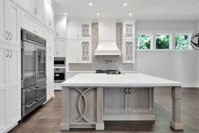 Huge transitional l-shaped dark wood floor and brown floor eat-in kitchen photo in Jacksonville with a farmhouse sink, white cabinets, quartz countertops, white backsplash, marble backsplash, stainless steel appliances, an island, white countertops and flat-panel cabinets