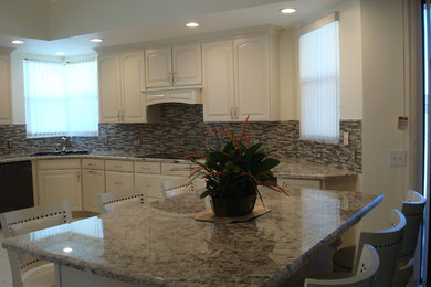Example of a mid-sized classic l-shaped porcelain tile and beige floor eat-in kitchen design in Miami with a drop-in sink, raised-panel cabinets, beige cabinets, granite countertops, brown backsplash, glass sheet backsplash, black appliances and an island