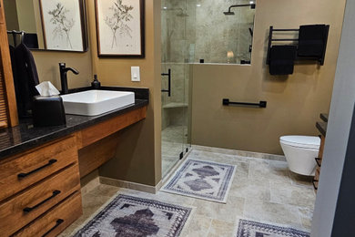 Example of a mid-sized arts and crafts master multicolored tile and ceramic tile ceramic tile, multicolored floor, single-sink and vaulted ceiling corner shower design in Kansas City with shaker cabinets, medium tone wood cabinets, a wall-mount toilet, a vessel sink, granite countertops, a hinged shower door, a niche, a floating vanity and beige walls