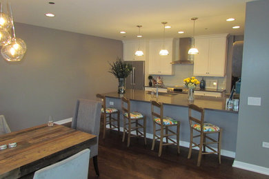 Open concept kitchen - large transitional l-shaped medium tone wood floor open concept kitchen idea in Chicago with a single-bowl sink, shaker cabinets, white cabinets, quartz countertops, green backsplash, glass tile backsplash, white appliances and a peninsula