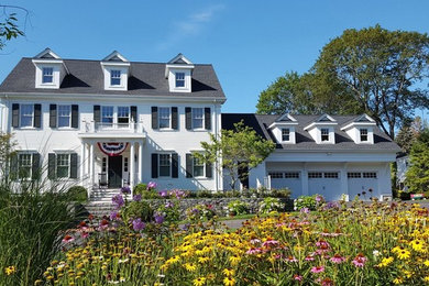 This is an example of a large traditional two-storey white house exterior in Boston with vinyl siding, a gable roof and a tile roof.