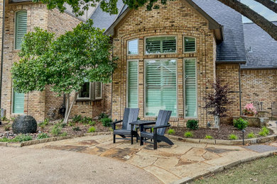 This is an example of a mid-sized traditional full sun front yard stone landscaping in Dallas for summer.