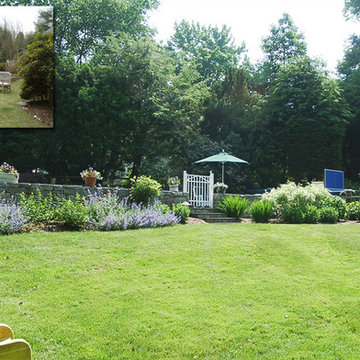 Perennial and flowering shrub masses complement a stone wall. New planting beds