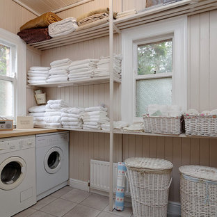 Imagen de cuarto de lavado clásico con armarios abiertos, paredes beige, lavadora y secadora juntas y suelo gris