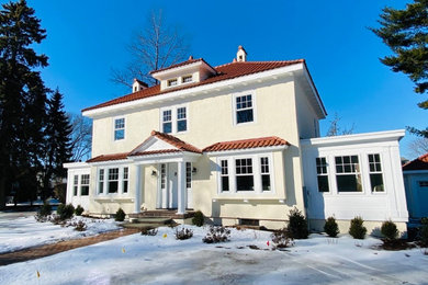 Example of a classic beige three-story house exterior design in Boston with a hip roof, a tile roof and a red roof