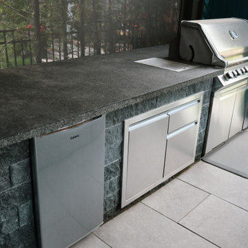 Built-In Outdoor Kitchen with Stone Cabinetry Under Pergola