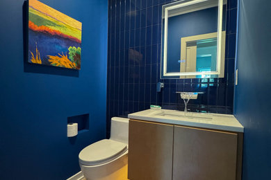 Powder room - small blue tile and glass tile light wood floor and brown floor powder room idea in DC Metro with flat-panel cabinets, light wood cabinets, a one-piece toilet, blue walls, an undermount sink, quartzite countertops, white countertops and a floating vanity