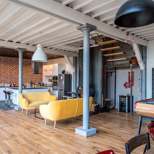 Foto de salón abierto, industrial, grande, con paredes negras, suelo de madera clara, estufa de leña, marco de chimenea de metal y suelo marrón