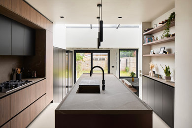 Inspiration for a medium sized contemporary single-wall kitchen/diner in London with a built-in sink, flat-panel cabinets, dark wood cabinets, grey splashback, an island, grey floors, grey worktops and exposed beams.