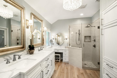 Corner shower - mid-sized transitional master gray tile and marble tile porcelain tile and brown floor corner shower idea in Dallas with recessed-panel cabinets, white cabinets, gray walls, an undermount sink, quartz countertops, a hinged shower door and white countertops