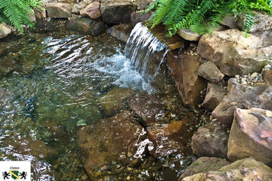 Photo of a rustic backyard stone water fountain landscape in Cleveland.