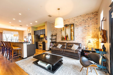 Example of a large urban open concept light wood floor, yellow floor and brick wall living room design in Dallas with beige walls