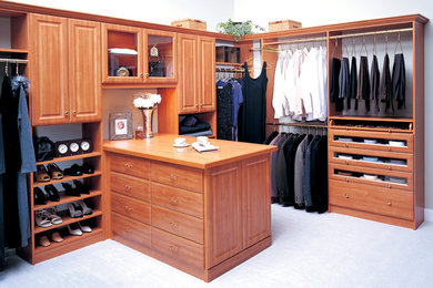 Example of a large classic gender-neutral concrete floor and white floor walk-in closet design in Baltimore with raised-panel cabinets and medium tone wood cabinets