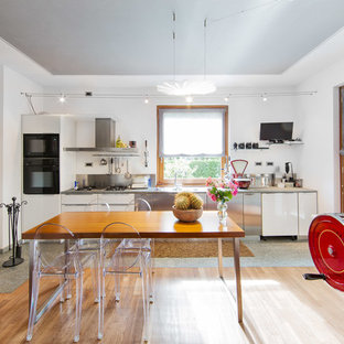 Exemple d'une grande salle à manger ouverte sur la cuisine éclectique avec un mur blanc, un sol en bois clair et une cheminée ribbon.