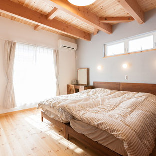 Immagine di una camera da letto etnica con pareti bianche, pavimento in legno massello medio e pavimento marrone