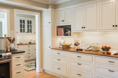 Photo of a large traditional kitchen pantry in New York with no island, flat-panel cabinets, white cabinets, wood benchtops, white splashback, subway tile splashback, stainless steel appliances, a single-bowl sink and light hardwood floors.
