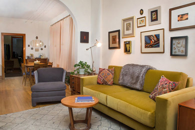 Small transitional enclosed medium tone wood floor living room photo with white walls and a tv stand