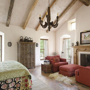 Réalisation d'une grande chambre parentale bohème avec un mur blanc, un sol en brique, une cheminée standard et un manteau de cheminée en bois.