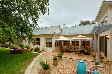 Large country backyard patio in Austin with natural stone pavers and a pergola.