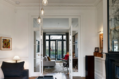 Medium sized traditional formal enclosed living room in London with white walls, dark hardwood flooring, a standard fireplace, a metal fireplace surround, no tv and brown floors.